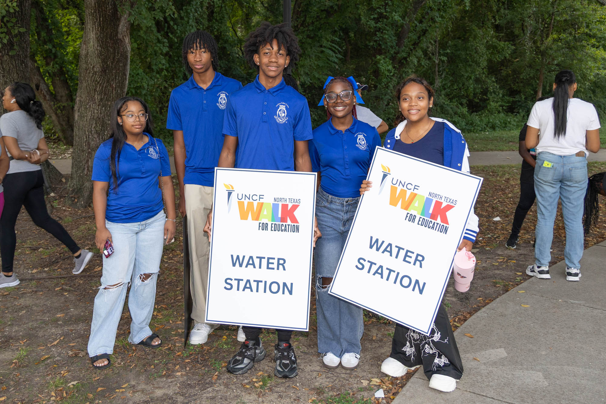 group of young adults to of the are holding a "water station" sign