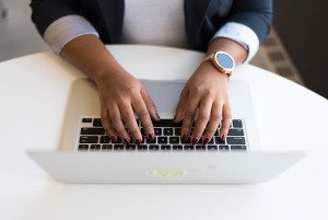 Black female's hands lay on a laptop keyboard. Photo from Flickr/WOCinTech Chat.