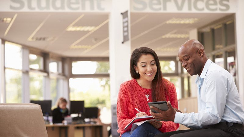 College Student Having Meeting With Tutor To Discuss Work