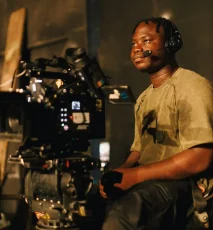 A Black man sitting in front of a camera filming. Photo by Ben Iwara on Unsplash.