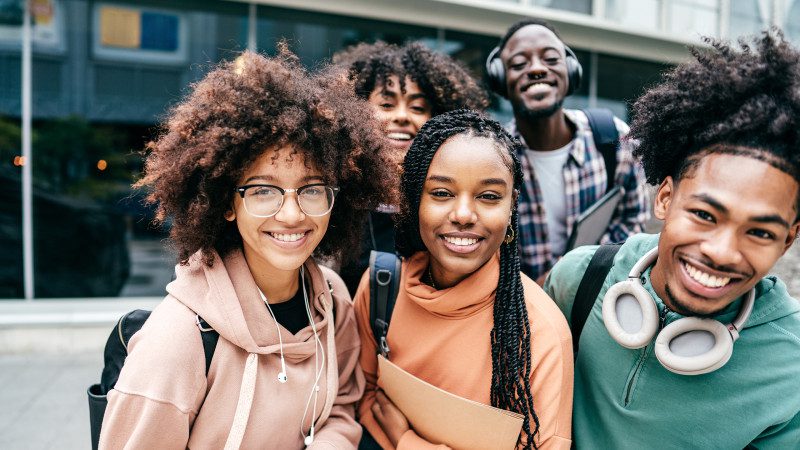 Group of college students smile outside a college building
