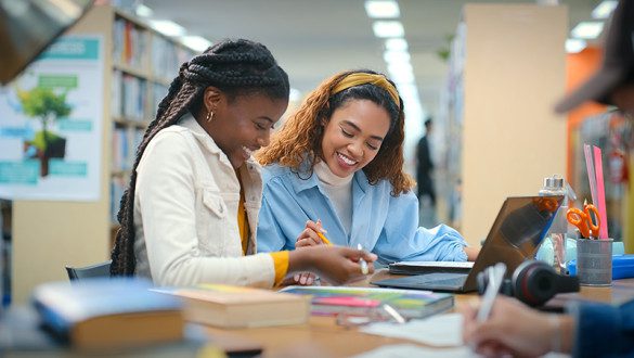 Two female college students working together at the library