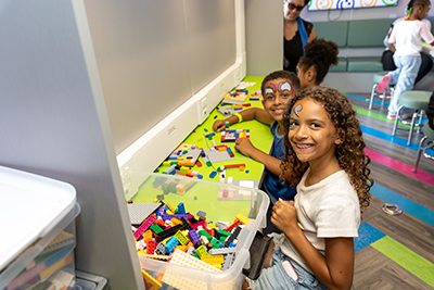 Group of kids enjoying Walk arts and crafts activities inside of a room. two of the children are smiling at the camera