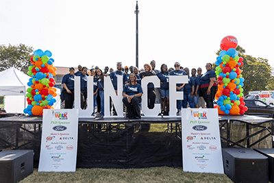 large group of people on stage. there are two balloon towers on either side of the stage in addition to two boards displaying the PHD sponsors