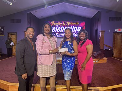 Four people presenting a donation check