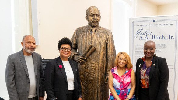 Four people standing around newly unveiled statue