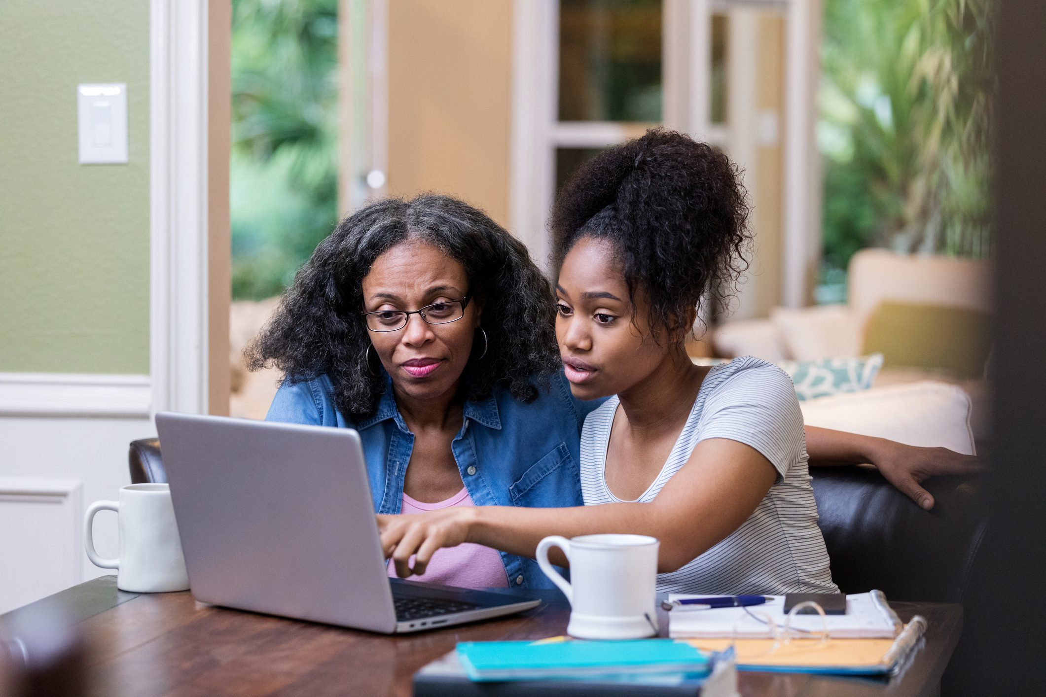Young woman shows her mom something on laptop