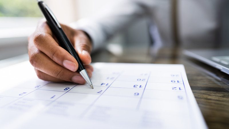 Calendar Deadline. Young Man Holding Pen Marking Date
