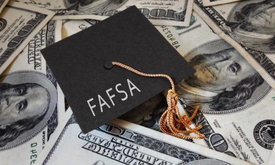 Graduation cap with the words FAFSA on top of money