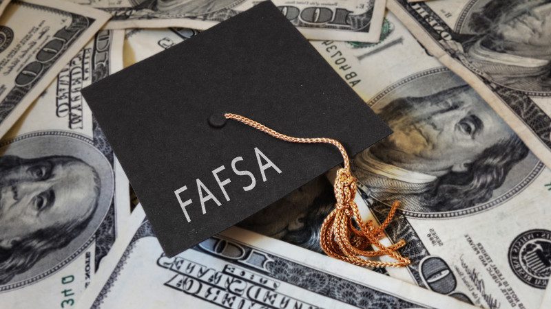 Graduation cap with the words FAFSA on top of money