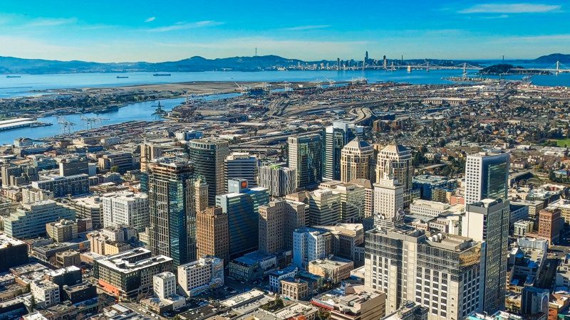 The City of Oakland CA with San Francisco in the background sits on the edge of the San Francisco Bay..