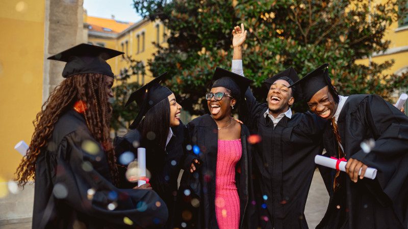 Happy black students celebrating graduation day at university campus
