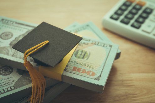 Graduation cap university on stack US dollar banknote,