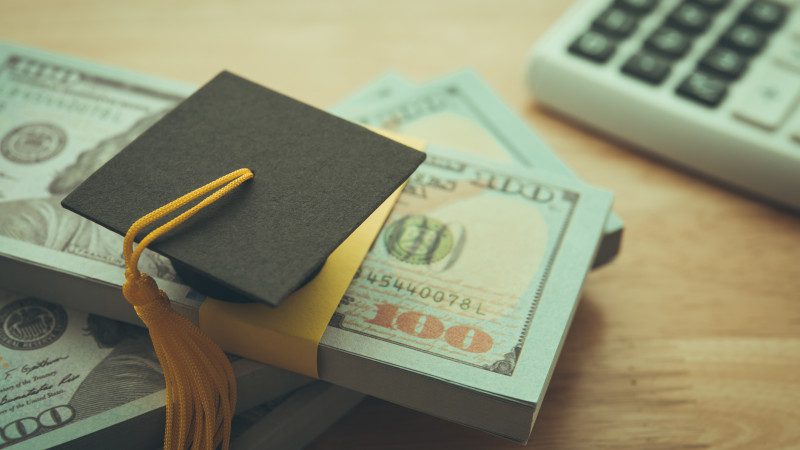 Graduation cap university on stack US dollar banknote,