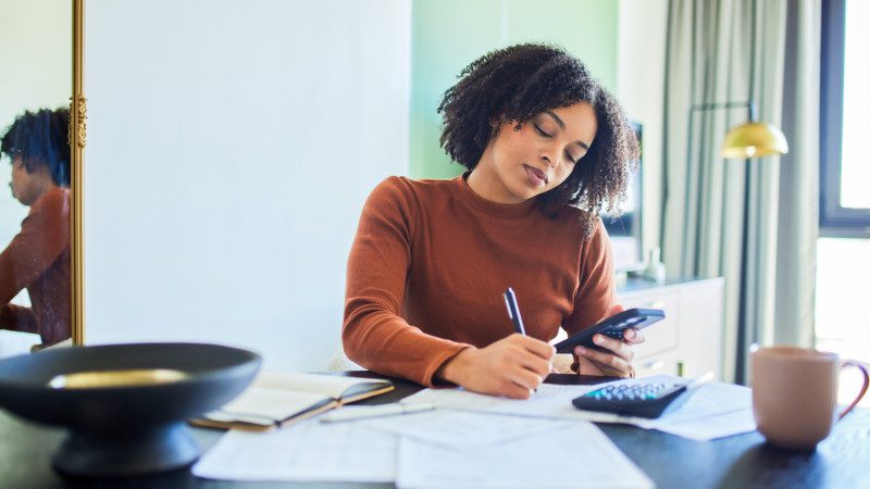 Focused Black Woman Working on Budget and Writing Notes at Home Desk