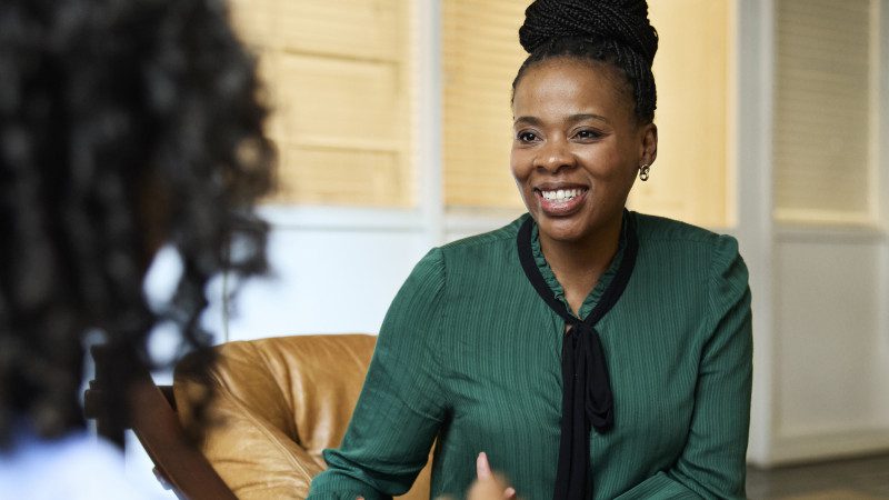 Smiling mature female business expert talking with coworker