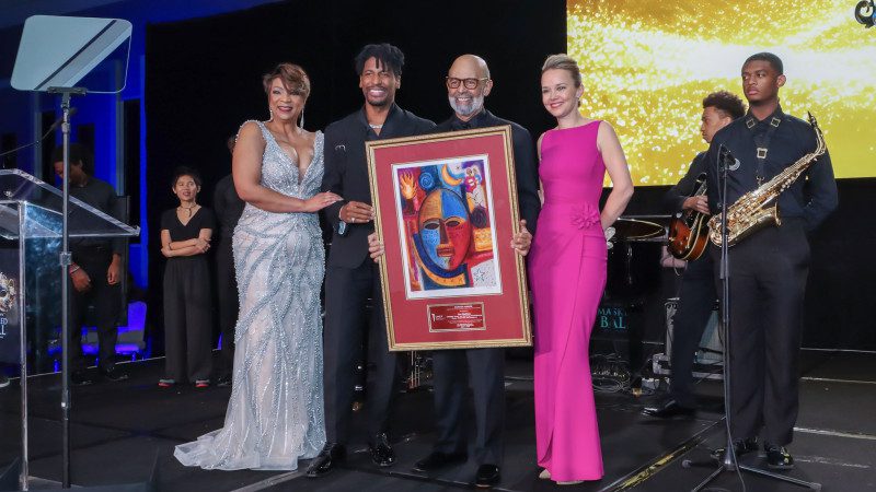 Event officials presenting Jon Baptiste with a painting