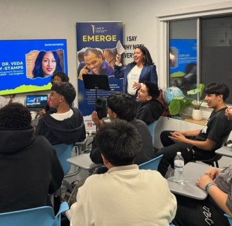 Dr. Veda Ramsay Stamps, regional development director, Los Angeles, UNCF, walks students and parents through applying for scholarships on UNCF's scholarship portal during an EMERGE College and Career Readiness Initiative workshop. Students sit in desks throughout the room.