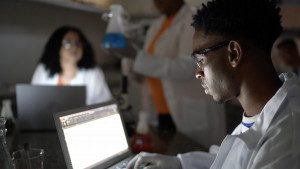 Male student checks results on laptop while working in a lab