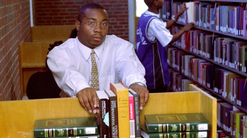 Male student with books in campus library
