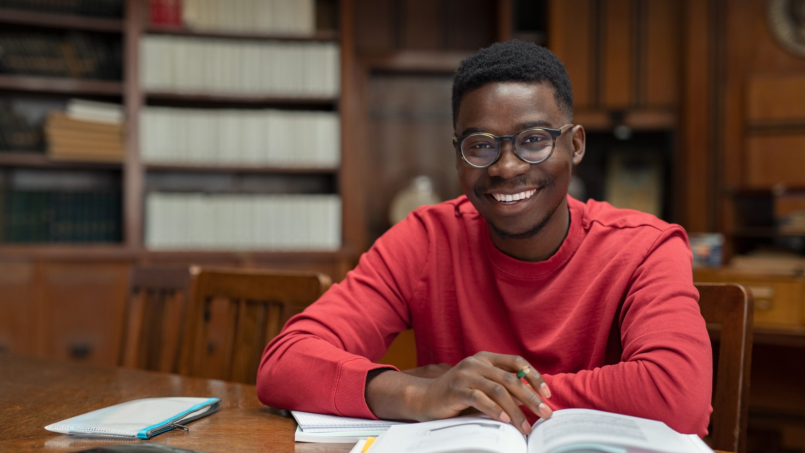 Man with books smiling in library