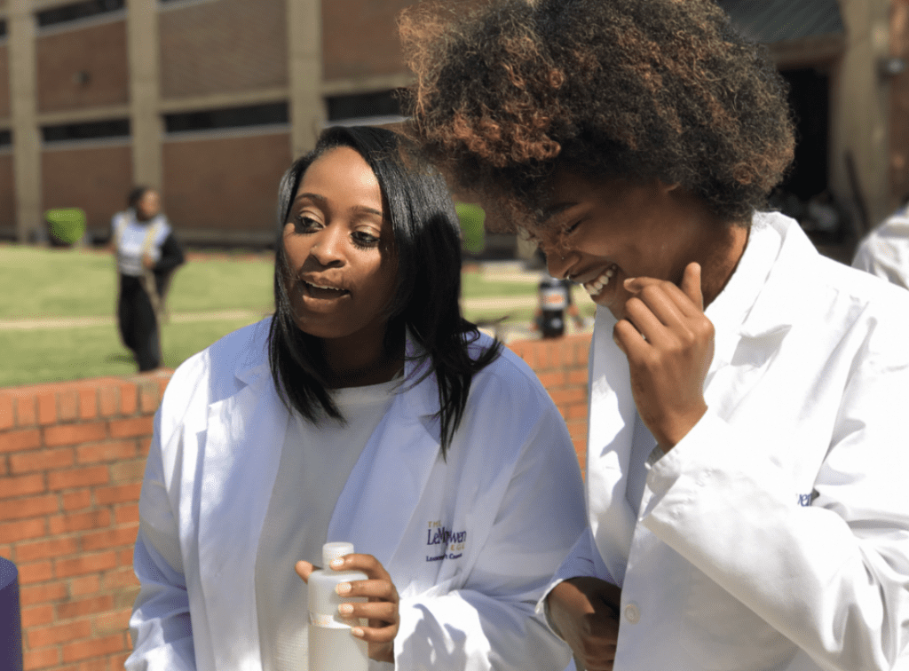 2 female Lemoyne Owen College students wearing lab coats talking outside
