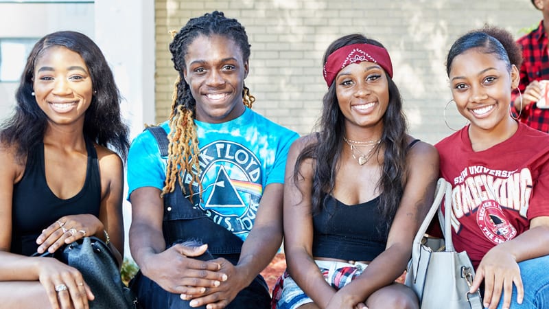 4 Shaw University students smiling outside on campus