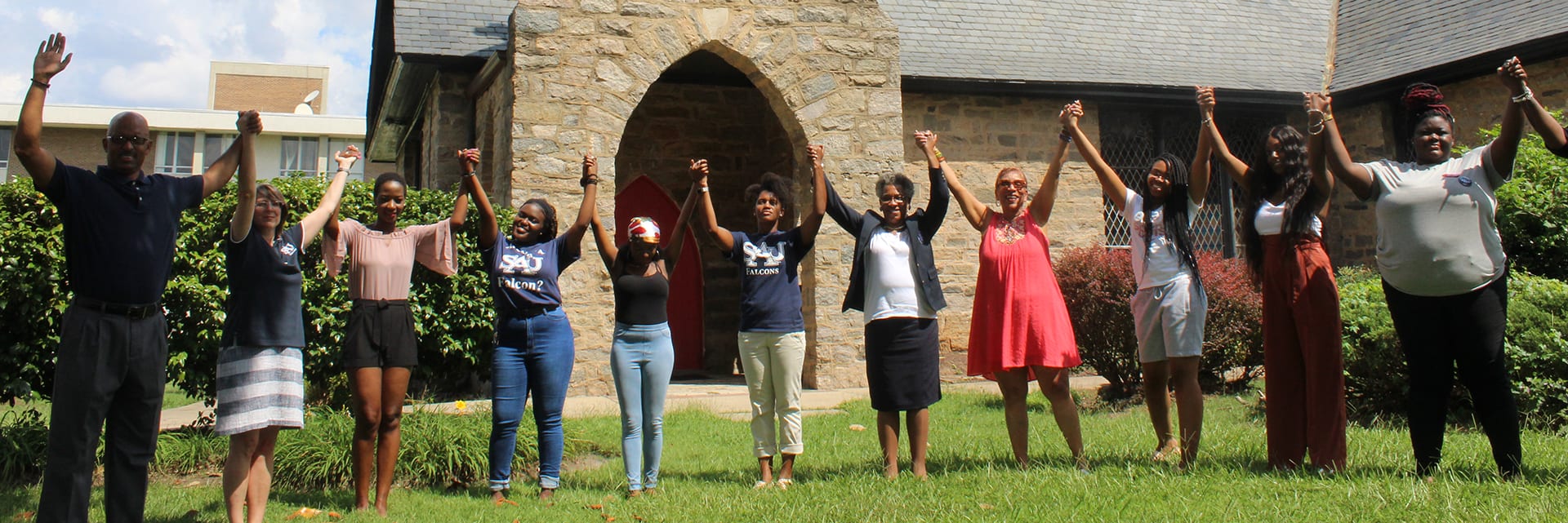 Group of students with joined hands in front of campus church