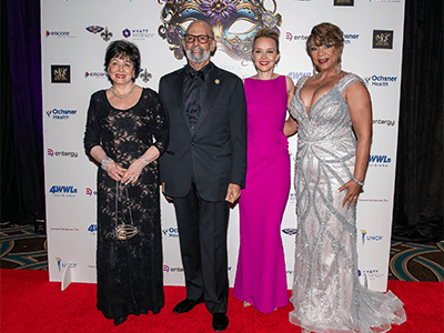 Group of event officials including Dr. Lomax posing in front of Step n Repeat
