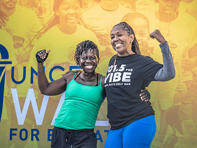 Two event attendees people posing in front of step n repeat