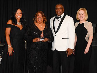Group of four event attendees. The one second from left has an award in her hand