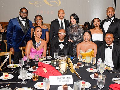 Group of event attendees gathered around table. Some seated and some standing