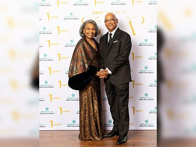 Two event attendees in front of step n repeat
