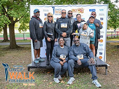 group of event attendees posing in front of step n repeat