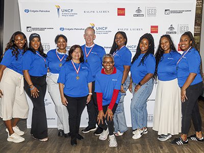 A group of volunteers posing in front of a sponsor banner