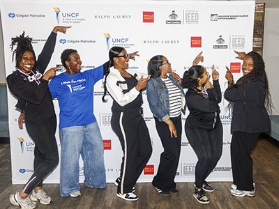 A group of students posing in front of a sponsor banner