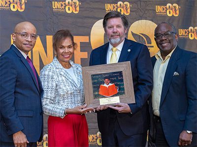 Four event attendees. Two in the middle are holding a picture