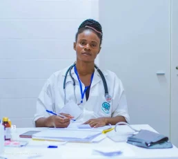 Black woman doctor wearing a stethoscope writing notes at a table. Photo by Francisco Venâncio on Unsplash.