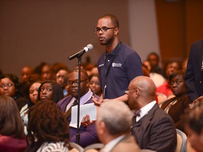 Male student asking question at microphone during large group meeting