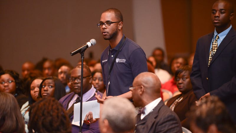 Student speaking at microphone during large gathering