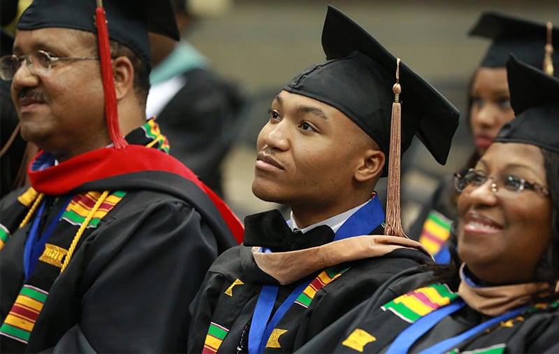 College graduates in caps and gowns listening during graduation ceremony