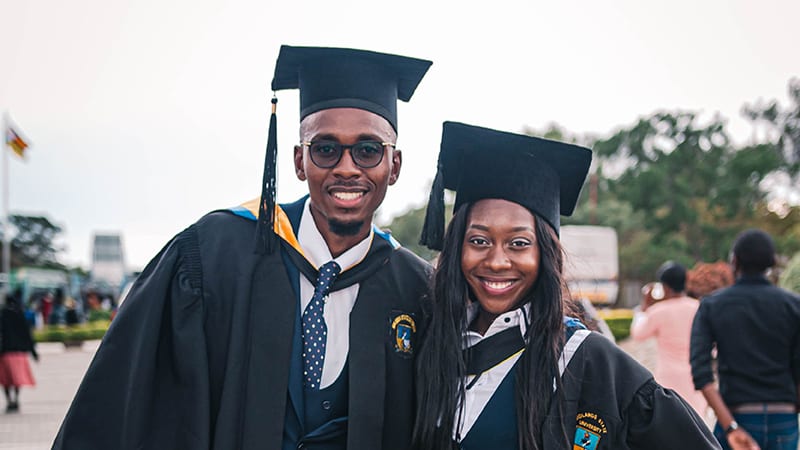 A male and female college graduate smile for the camera