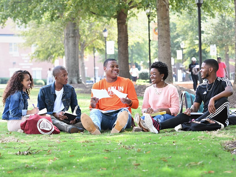 5 Claflin University students sitting on grassy campus outdoors