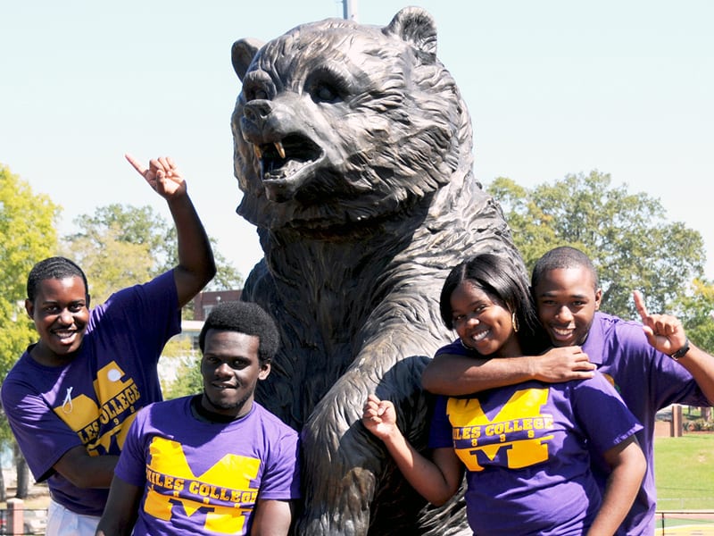 4 Miles College students standing next to bear statue