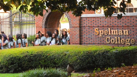 Group shot of Spelman College students walking outside past college sign