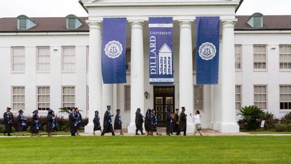 Dillard University building with graduates wearing caps and gowns walking in front