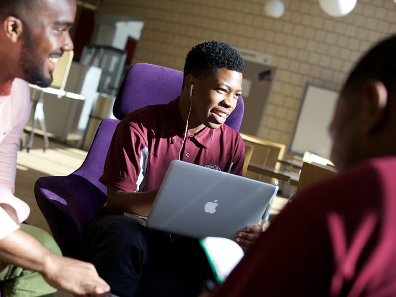 3 male students studying and talking with laptop at Morehouse College