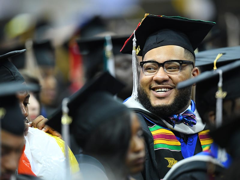 Oakwood University students smiling during graduation ceremony wearing caps and gowns