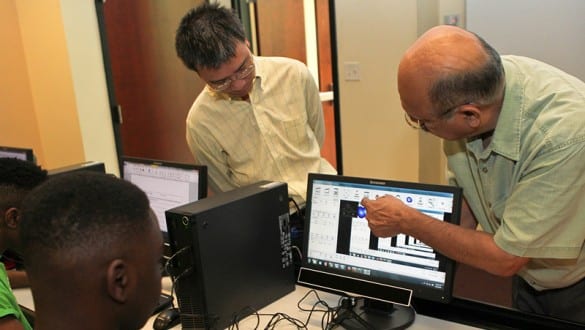 Students working together on computers with professor