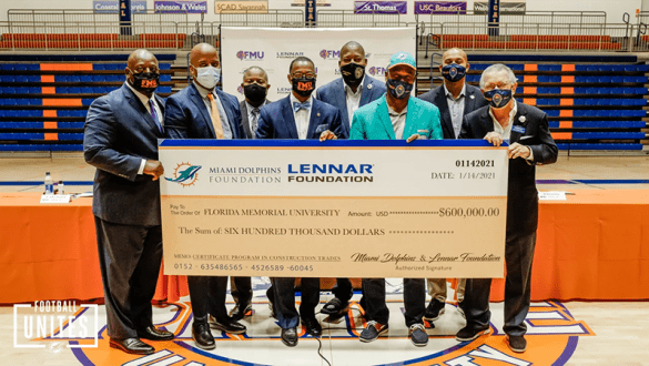 A group holds up a donation check for $600,000 from the Miami Dolphins